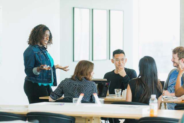 Adult speaks to college kids sitting at a table