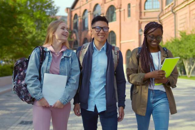 Two female and one male college student walk on campus.