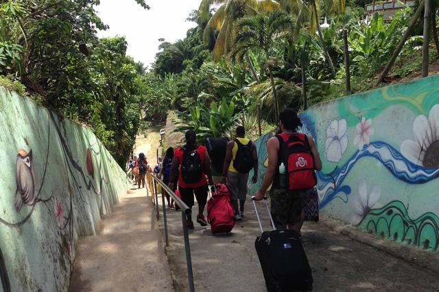 Students walk down a path with drawings on the walls and lush vegetation