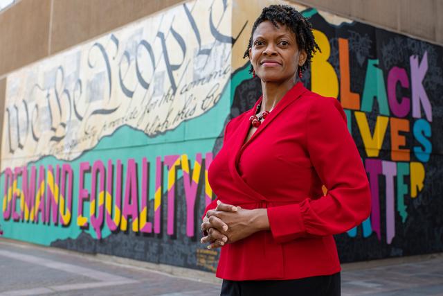 Andrea Williams in a red blouse in front of graffiti