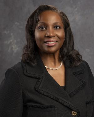 Lisa Cook, a Black woman in a black suit with pearls.