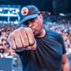 Chuck D with his arm raised straight ahead in a fist