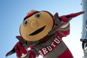 Brutus Buckeye points his fingers at a camera