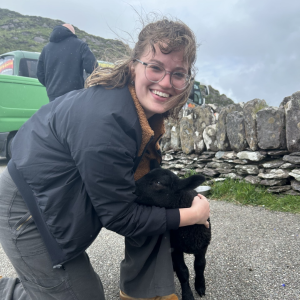 Maddie Dougherty kneeling by a baby goat