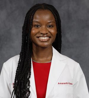 Ami Kanu, a Black woman, in her physician's white coat and scarlet blouse